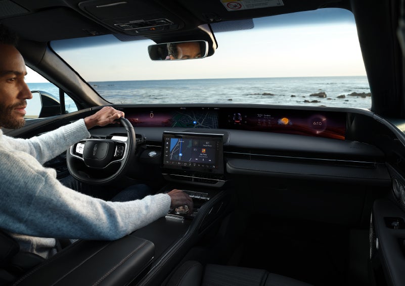 A driver of a parked 2024 Lincoln Nautilus® SUV takes a relaxing moment at a seaside overlook while inside his Nautilus. | Doral Lincoln in Doral FL