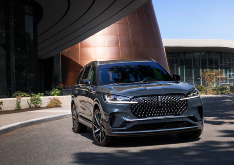 A gray 2025 Lincoln Aviator® SUV is parked outside a modern building with the sun shining. | Doral Lincoln in Doral FL