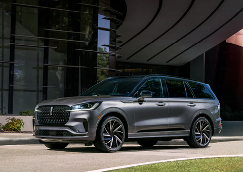 A gray 2025 Lincoln Aviator® SUV is parked outside a modern building showcasing the driver’s side of the vehicle. | Doral Lincoln in Doral FL