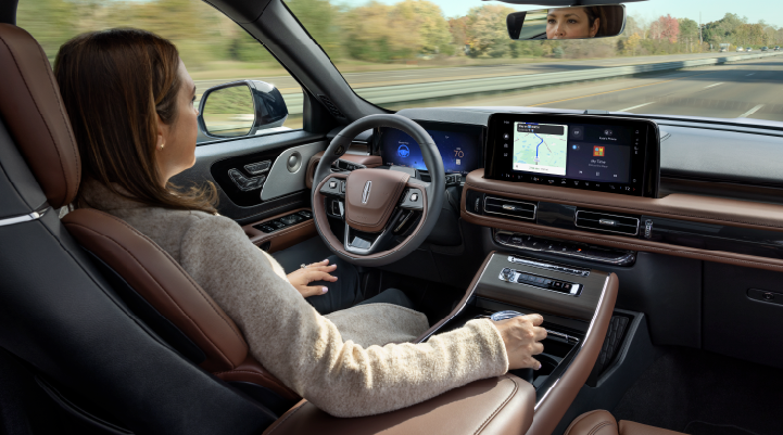 A woman is seen sitting in the driver’s seat of her 2025 Lincoln Aviator® SUV with her hands off the steering wheel. | Doral Lincoln in Doral FL
